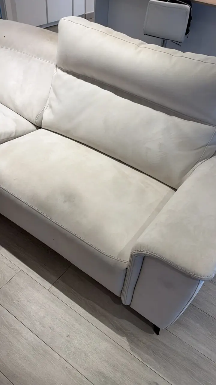Asiento y respaldo de un sofá blanco con manchas oscuras antes de la limpieza