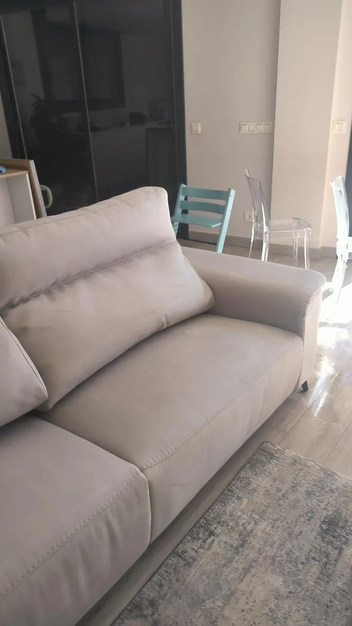 Asiento y reposabrazos de un sofá blanco después de la limpieza a domicilio